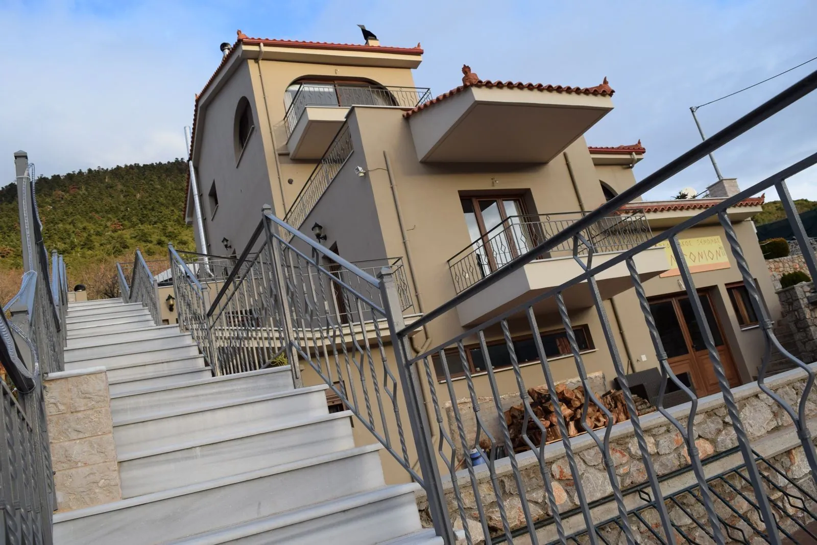 Η πέτρινη σκάλα με τα κάγκελα που ανεβαίνει στον ξενώνα